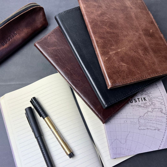 Collection of leather-bound notebooks and a pen on a gray surface